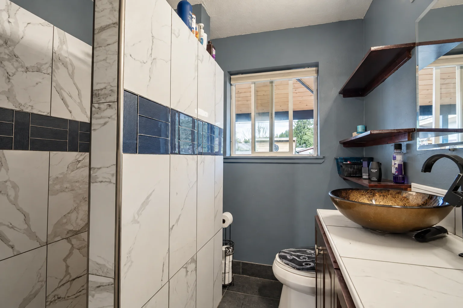 Completed bathroom with vessel sink, wood vanity and tiled shower